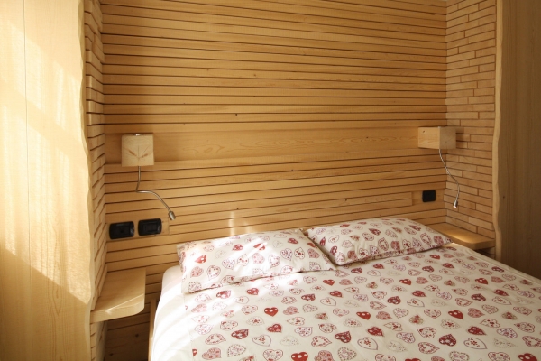 letto hotel testata parete legno